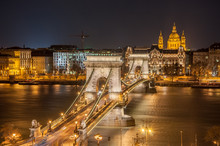 Night View Of The Szechenyi Chain Bridge And Church St. Stephen's In Budapest