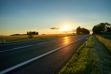 Wall Mural - empty asphalt road in a rural landscape at sunset.