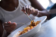 © .shock - a young African American woman eating pasta