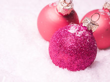Three Pink Christmas Baubles In Snow