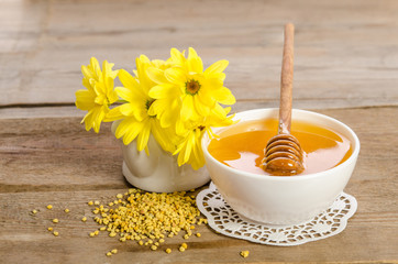 Yellow flowers and bee products (honey, pollen) on wooden backgr