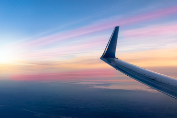 Wall Mural - Wing of a plane from the window on sunset. Sunny colorful sky background.