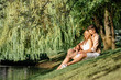 © Loginova - Romance and love. Dating and park. Loving couple sitting together on grass near the lake.