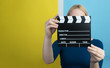 © Myvisuals - Young woman holding a clapperboard over colorful backgound