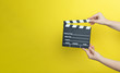 © Myvisuals - woman holding movie clapper on yellow background, cinema concept