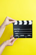© Myvisuals - woman holding movie clapper on yellow background, cinema concept