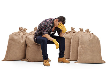 Canvas Print - Depressed farmer sitting on a burlap sack