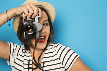 Fashion young girl makes the photo with old camera. Blue backgro