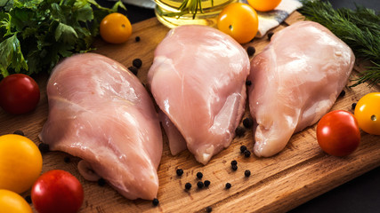 Raw chicken breast fillets and vegetable on wooden background