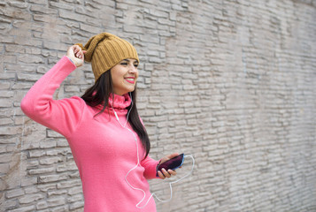 Young woman listening to music in headphones and dancing on bric