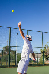 Wall Mural - Professional tennis player is doing a kick tennis on a tennis court on a sunny summer morning. The is dressed in sportswear. 