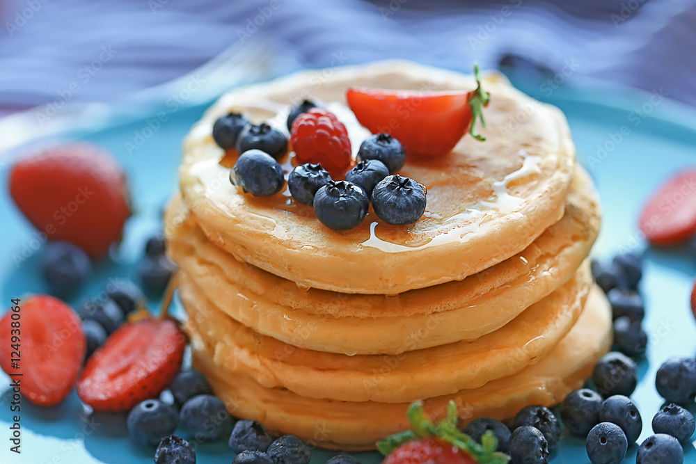 Tasty pancakes with berries on blue plate, close up view