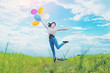 Happy girl jumping with colorful balloons outdoors. Young woman