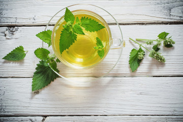 Wall Mural - green melissa herbal tea in glass cup on wooden background