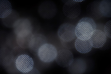 Wall Mural - Bokeh dark white mesh circles on black background. Abstract music background.