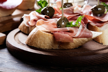 Sticker - Spanish tapas with slices jamon serrano, salami, olives and cheese cubes on a wooden table