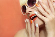Sunny orange manicure with dots on the women's nails and makeup closeup in sunglasses.