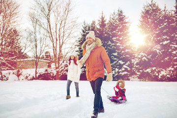 Wall Mural - happy family with sled walking in winter outdoors