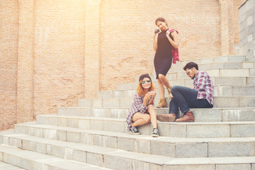 Wall Mural - Group of hipster students sitting on a staircase talking and rel