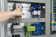 Hand eines Elektrikers zeigt auf eine Sicherung in einem Schaltschrank