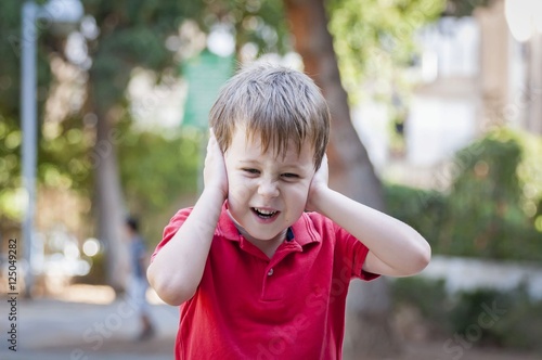 Valokuva Stressed out little boy closed his ears and screams, stock image.
