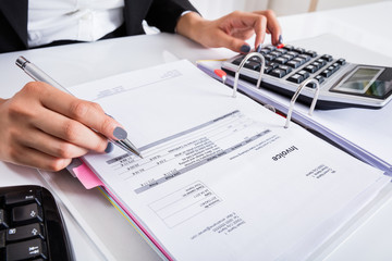 Businesswoman Calculating Invoice Using Calculator