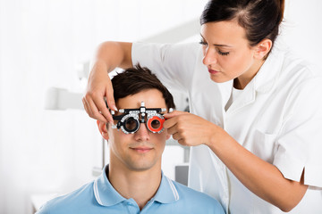 Female Optometrist Checking Patient's Vision With Trial Frame