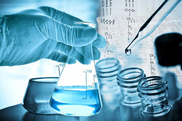Wall Mural - flask in scientist hand with test tubes in laboratory