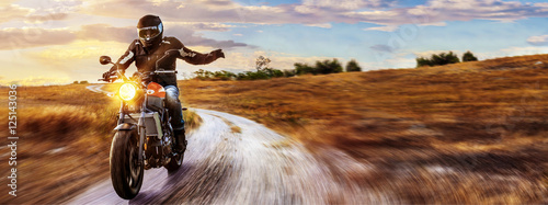 motocykl-jadacy-po-wiejskiej-drodze-o-zachodzie-slonca