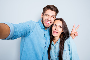 Wall Mural - Funny couple showing tongues and gesturing v-sign while making s