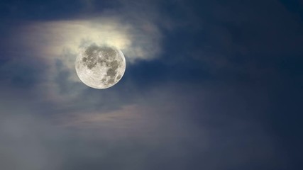 Wall Mural - fog moves across a full moon framed against a moody, blue sky with cloud cover..