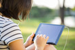 © paulovilela - Young woman using tablet in park