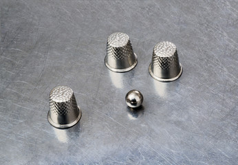 thimbles and a ball on a silver background