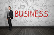 © gearstd - Businessman standing near red word 'Business'.