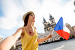 Young female tourist with czech flag making self portrait on the old town square of Prague. Enjoying great vacation in Czech republic