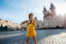 Young Woman In Yellow Walking With Smart Phone On The Old Town Square In Prague City