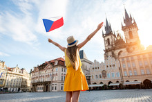 Young Female Tourist Dressed In Yellow Holding Czech Flag On The Old Town Square Of Prague. Enjoying Great Vacation In Czech Republic