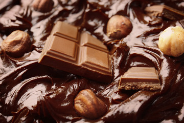 Delicious melted chocolate with pieces and nuts, closeup