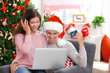 Wall Mural - Young couple shopping online with credit card at home for Christmas