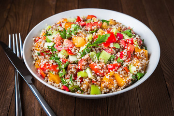 Wall Mural - Fresh healthy salad with quinoa, colorful tomatoes, sweet pepper, cucumber and parsley on wooden background close up. Food and health. Superfood meal.