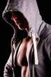 © SergeyCash - Close up portrait of sexual strong young man with muscular body in grey sport jacket hooded on dark background