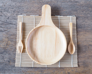 Wooden plate with handle and spoon with fork on table