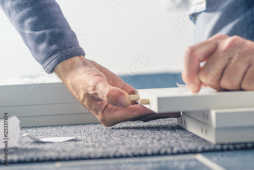 Fotografie, Tablou Man assembling furniture at home, hand with wooden dowel pins