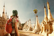 Woman traveling  with backpack and looks at Buddhist stupas