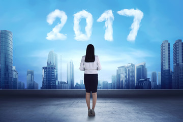 Asian business woman looking cloud shaped number 2017