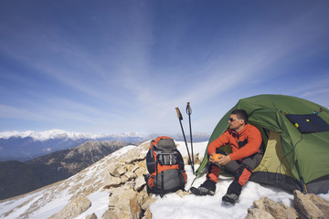 Winter camping in the mountains with a backpack and tent.