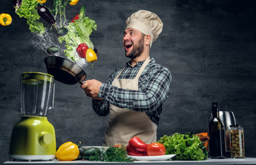 Wall Mural - Man cook holds a pan with vegetables flying in the  air.