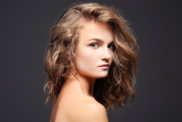 Portrait of beautiful young woman with long hair on grey background