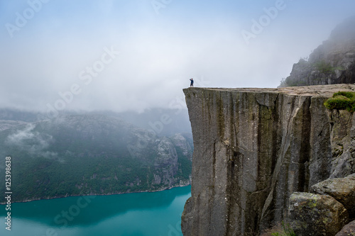 Tourist standing at Prekestolen rock's edge. Poster Mural XXL