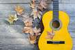 winter music symbol with autumn leaves and guitar on old wooden plank